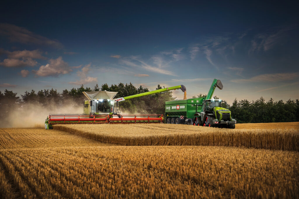 zdjęcie dwóch maszyn rolniczych; obie maszyny są na polu ze zbożem;kombajn marki CLAAS przesypuje skoszone na przyczepę;skup zbóż Krasnystaw;